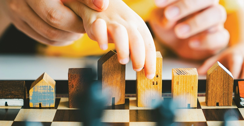 Person playing "chess" using blocks shaped like houses
