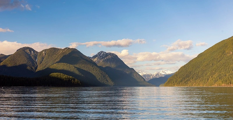 Image of a straight of water looking up towards two mountain ranges