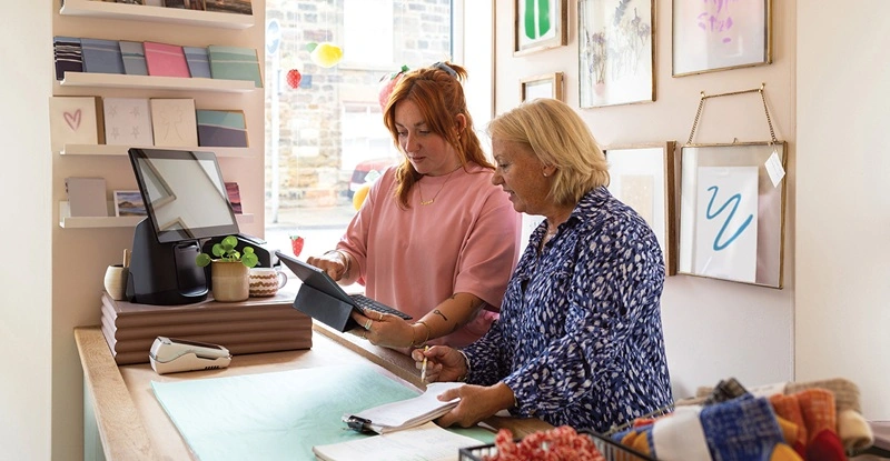 Two female shop owners, mother and daughter, standing behind the counter in a lifestyle store